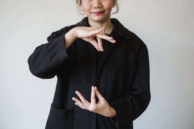 A woman in a studio using sign language against a white background.