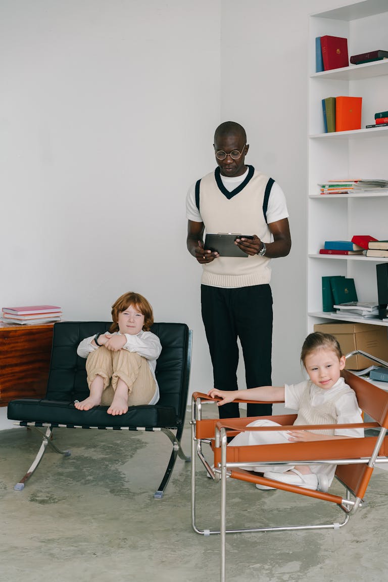 A psychologist conducting a counseling session with two children in a modern office setting.