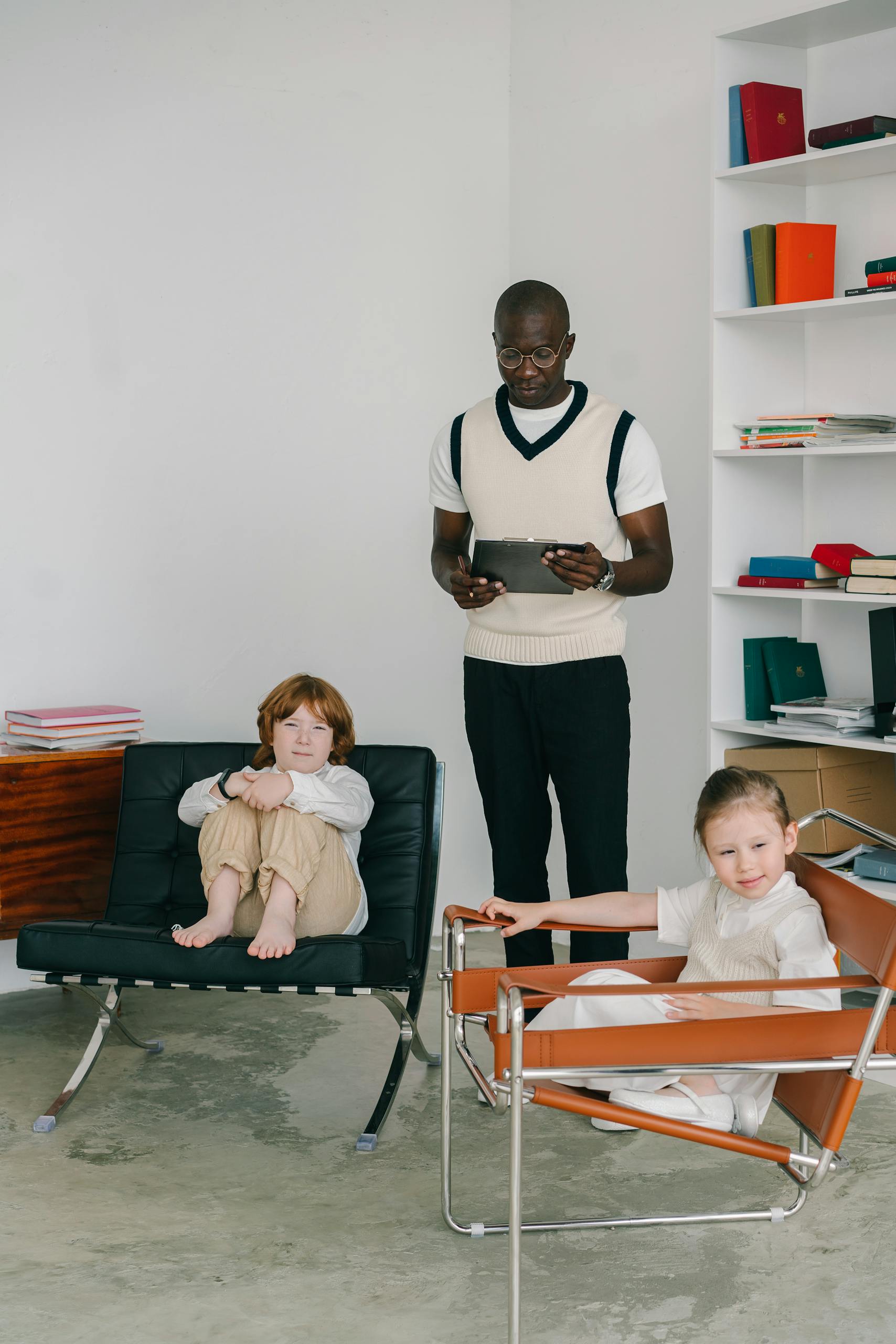 A psychologist conducting a counseling session with two children in a modern office setting.