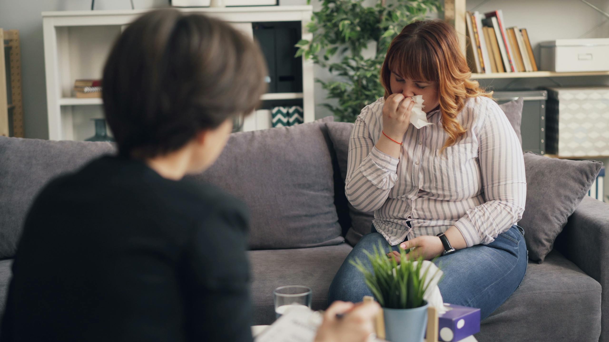 A woman in therapy expressing emotions during a counseling session indoors.