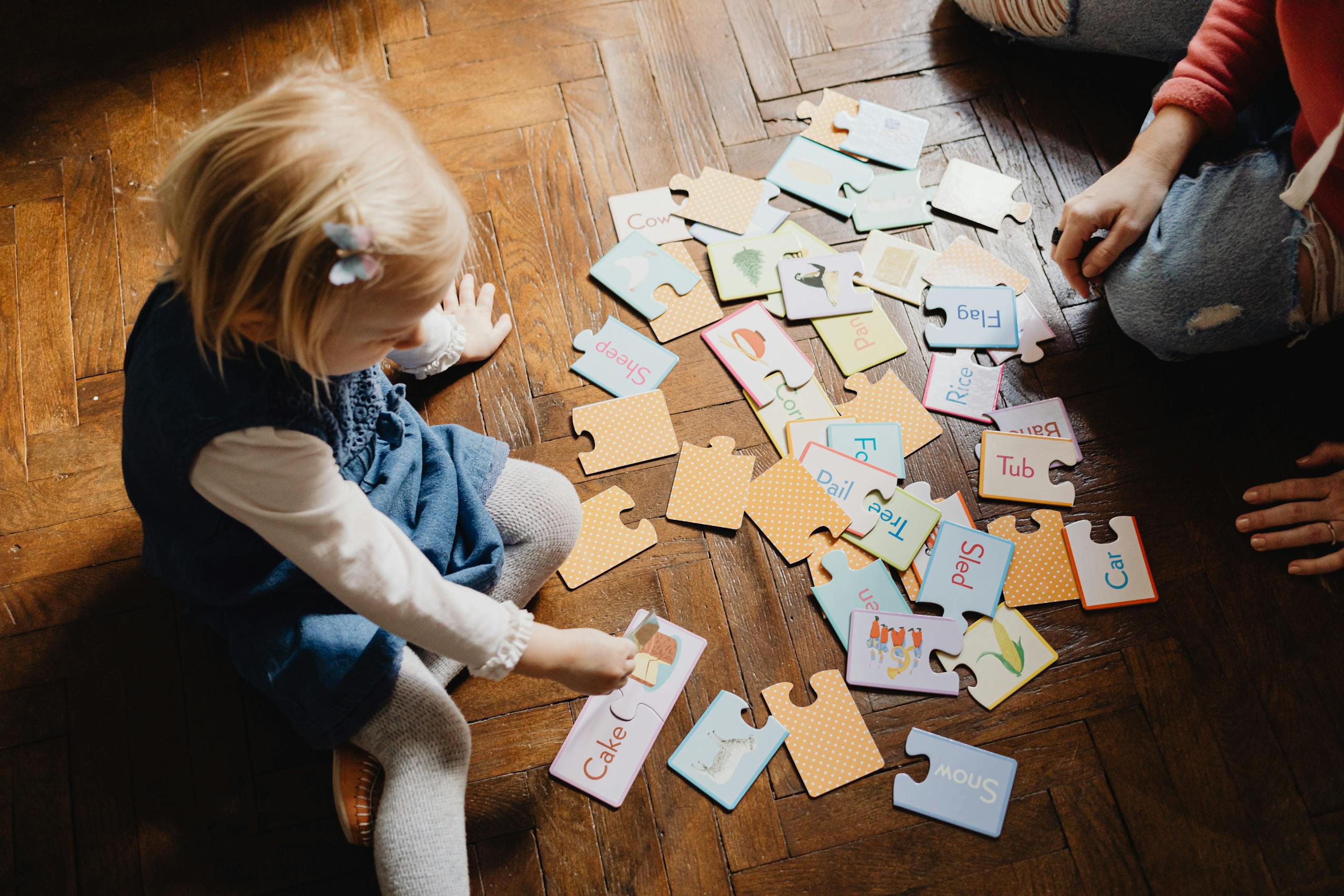 A young child engages with educational puzzles on a wooden floor, fostering learning and creativity.