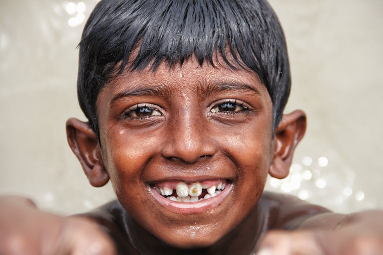 Close-up portrait of a young boy smiling with missing teeth, capturing joyful innocence.