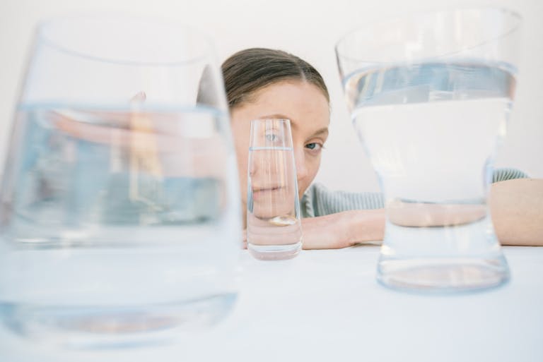 Creative portrait view distorted through various glass cups on a white background.