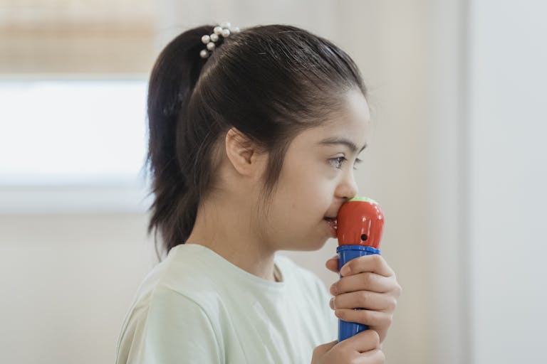 Side view of a young girl with Down syndrome engaging with a toy microphone.