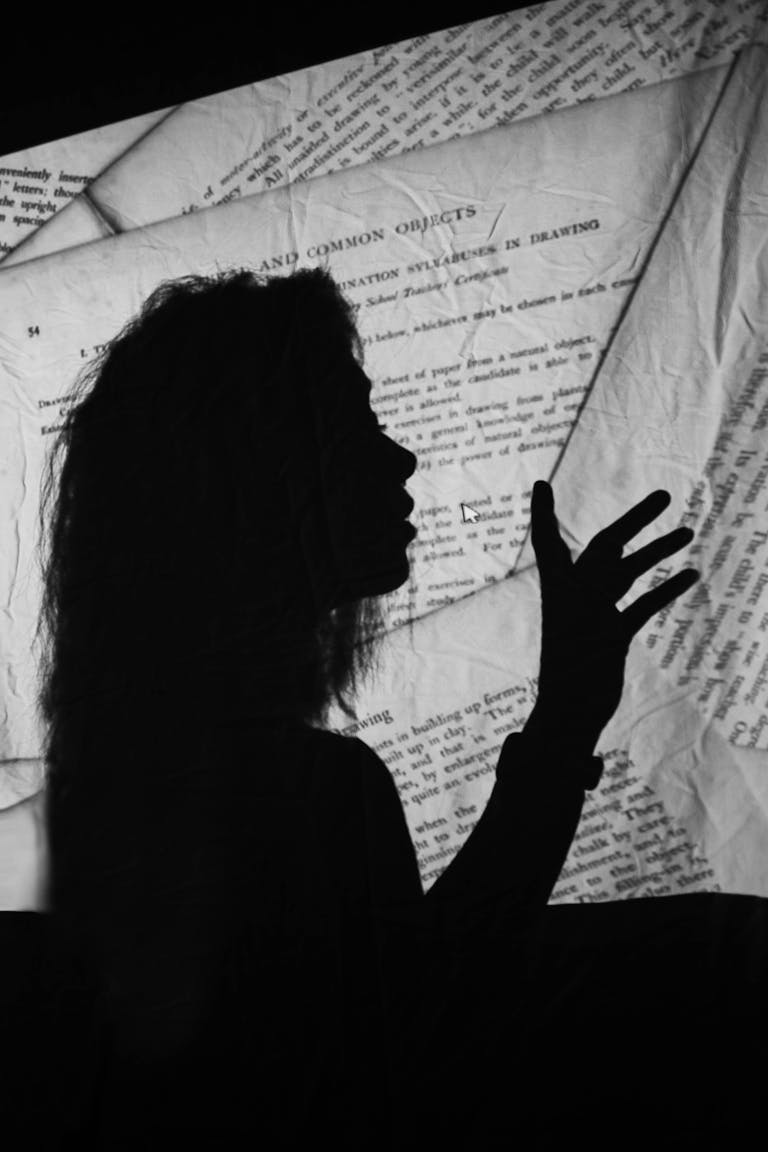 Silhouette of a woman gesturing with text background projected, conveying creativity and communication.
