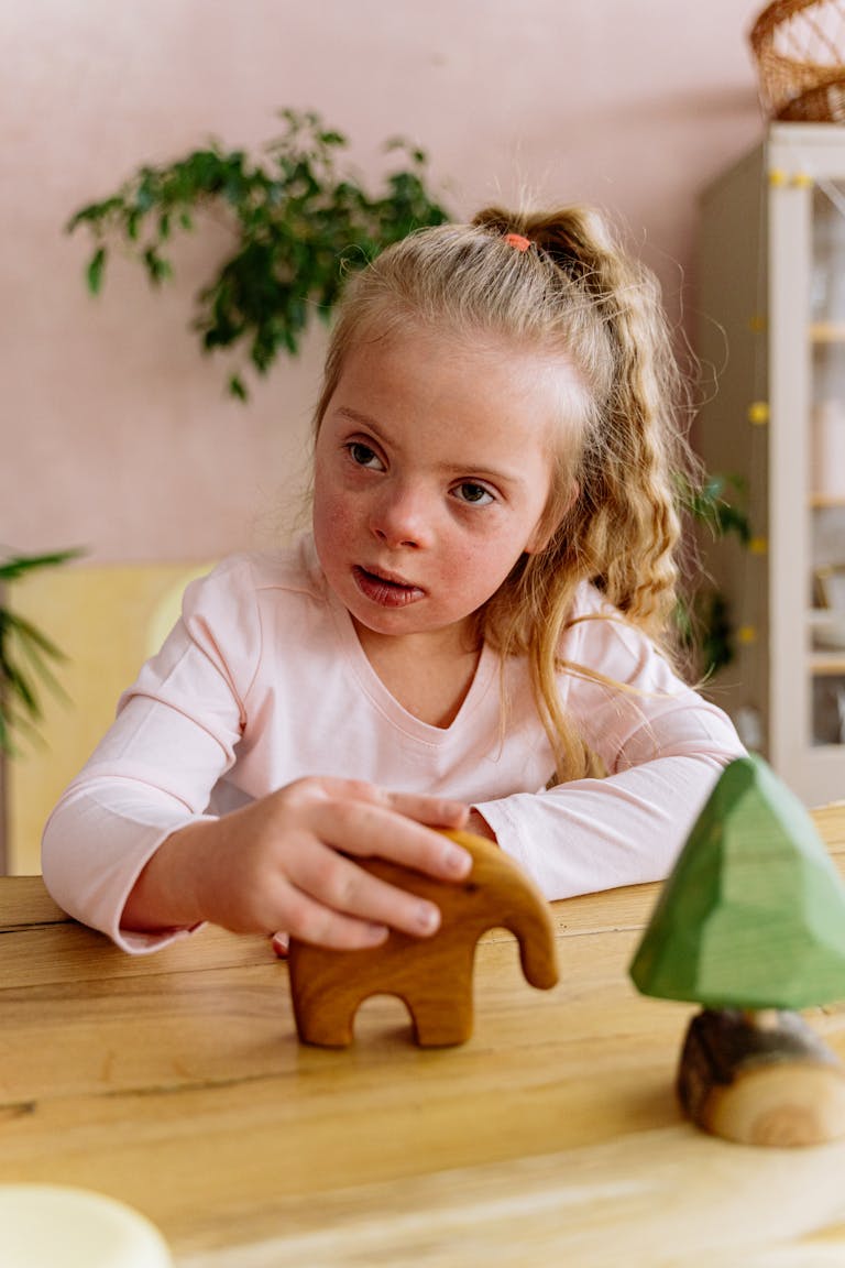 Young girl with Down Syndrome happily plays with wooden toys at a table indoors.