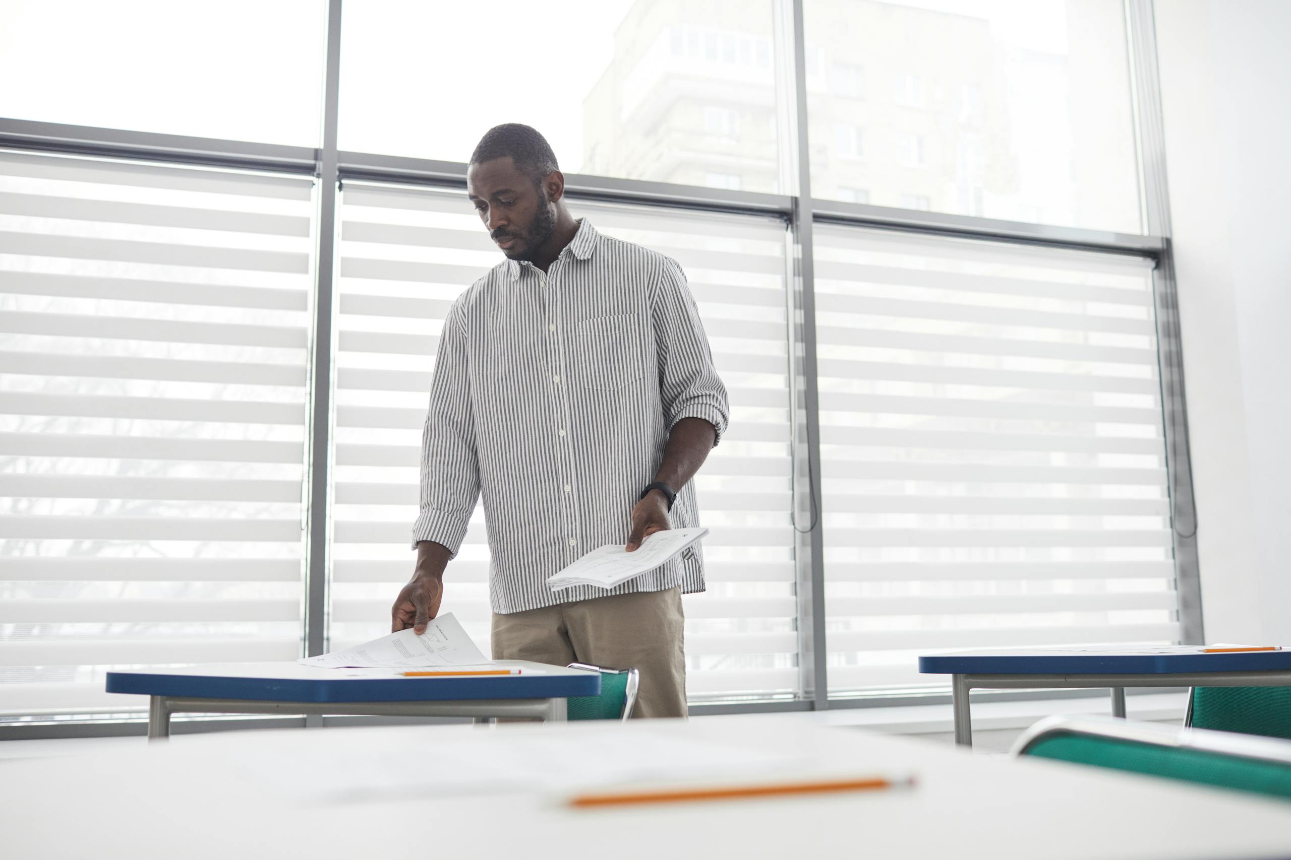 Educator sorting tests in a bright, contemporary indoor classroom setting.