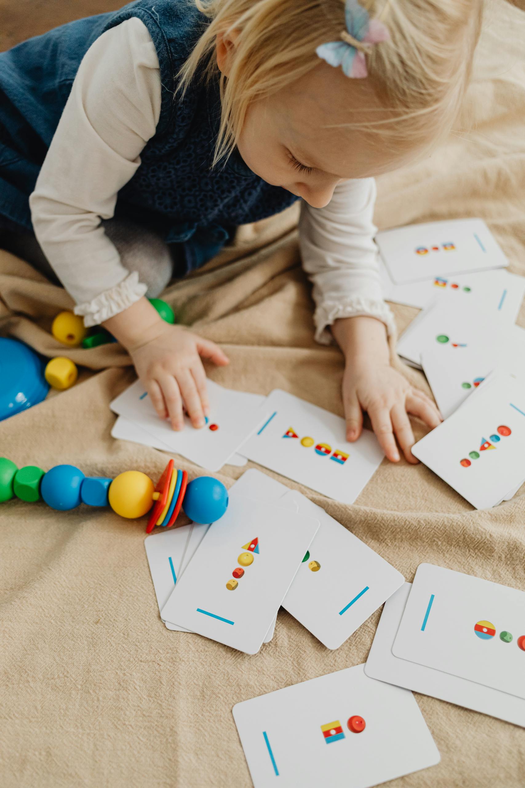 Young child playing with educational cards on a blanket indoors. Perfect for learning and development themes.